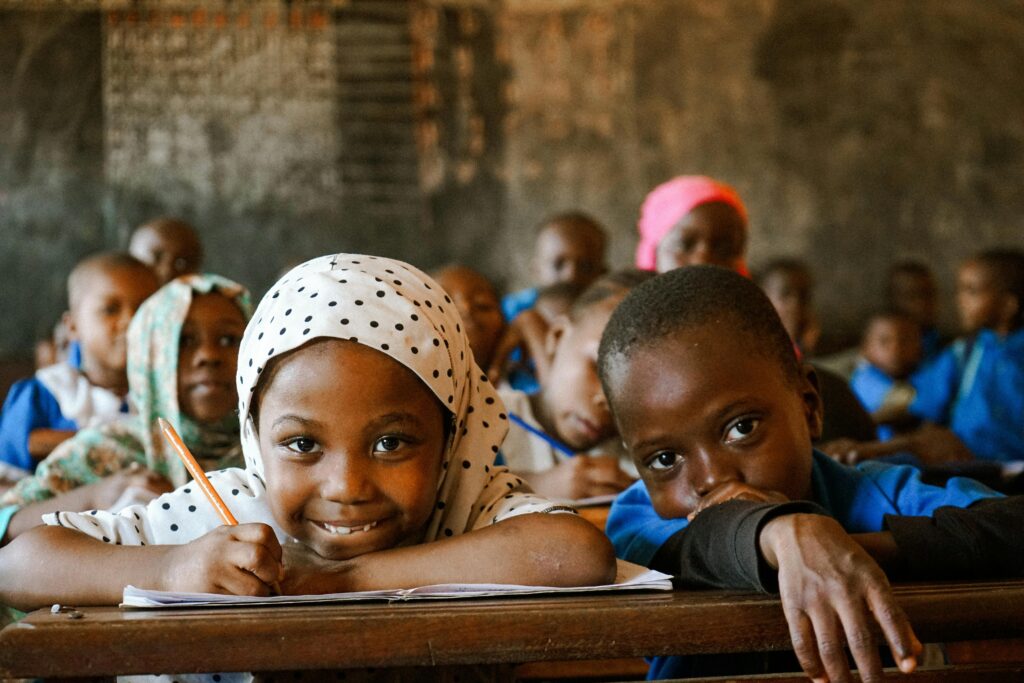 Happy children in African classroom, learning and smiling.