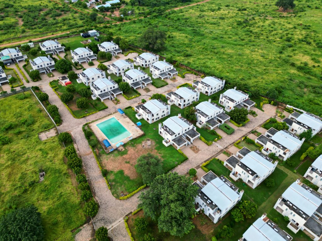 Aerial photograph of a modern housing estate with a communal pool, surrounded by lush greenery.